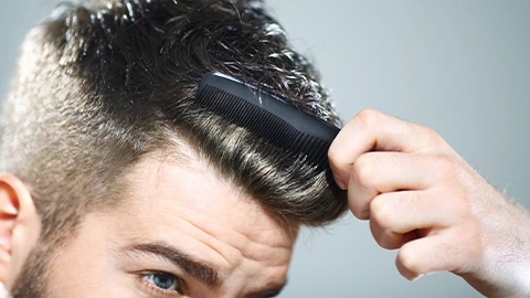 Un homme avec une coupe undercut se peigne les cheveux